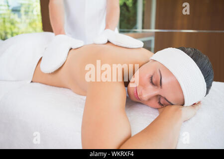 Beauty therapist rubbing womans back with heated mitts in the health spa Stock Photo