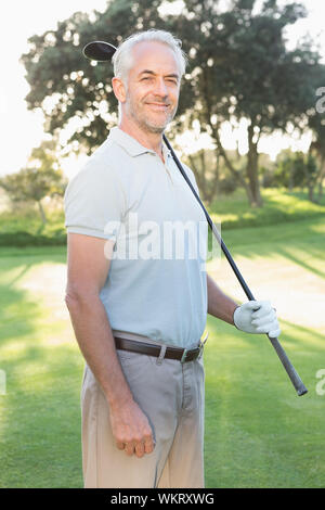 Smiling handsome golfer looking at camera on a sunny day at the golf course Stock Photo