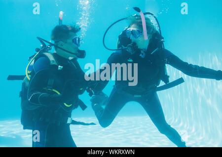 Friends on scuba training submerged in swimming pool  on their holidays Stock Photo