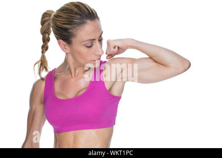 Female bodybuilder flexing bicep in pink sports bra on white