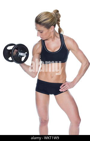 Female bodybuilder holding large black dumbbell with arm up looking at bicep on white background Stock Photo