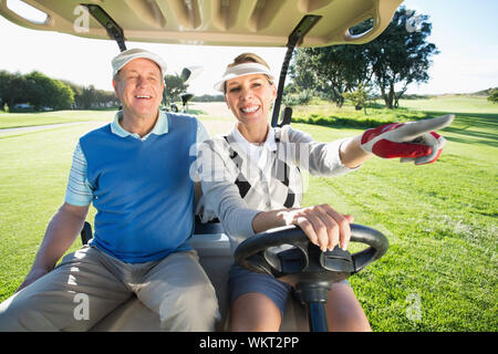 Happy golfing couple sitting in golf buggy on a sunny day at the golf course Stock Photo