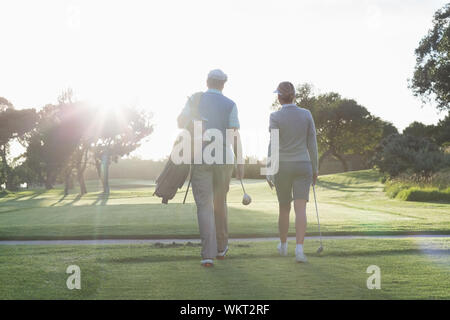Golfing couple walking and chatting on a sunny day at the golf course Stock Photo