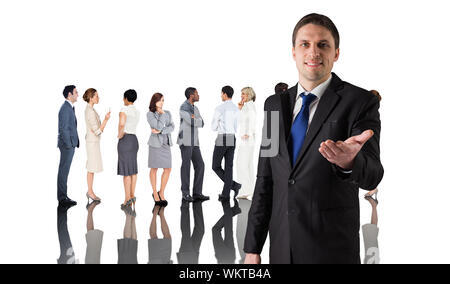 Composite image of handsome businessman holding hand out against group of workers Stock Photo