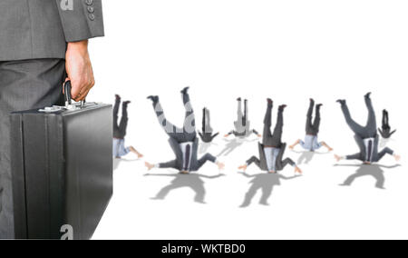 Composite image of businessman holding briefcase with business people hiding heads in ground Stock Photo