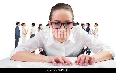 Composite image of businesswoman typing on a keyboard against group of workers Stock Photo