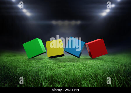 3d colourful cubes in a row against football pitch with bright lights Stock Photo