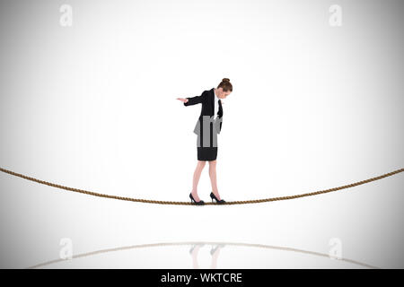 Businesswoman performing a balancing act on tightrope against white background with vignette Stock Photo