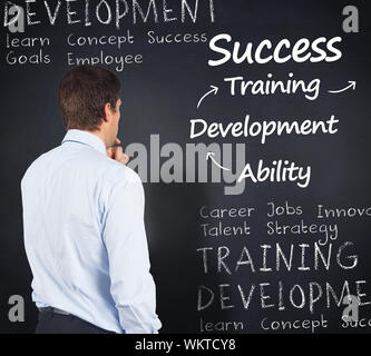Thinking businessman touching his chin against blackboard with business buzzwords Stock Photo