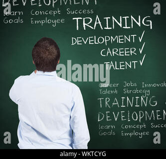 Businessman against green chalkboard with business buzzwords Stock Photo