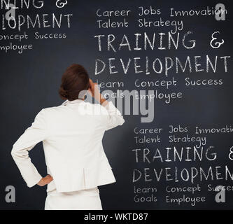 Thinking businesswoman against blackboard with business buzzwords Stock Photo