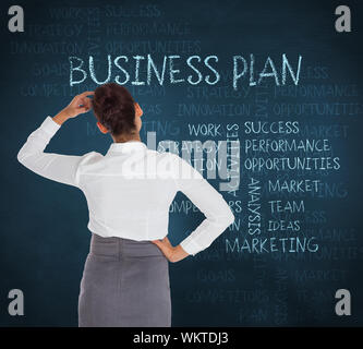 Businesswoman scratching her head against blue chalkboard with business buzzwords Stock Photo