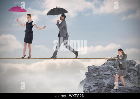 Young businesswoman pulling a tightrope for business people against rocky landscape Stock Photo