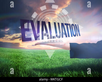 Businesswomans hand presenting the word evaluation against green field under orange sky Stock Photo