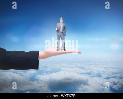 Smiling attractive architect on phone holding plans  against blue sky over clouds at high altitude Stock Photo
