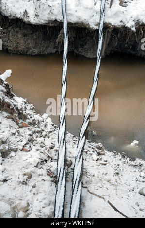 Laying a fiber optic and electricity cables in the frozen ground, buried cables for fast internet in rural region - underground cabling in Finland Stock Photo