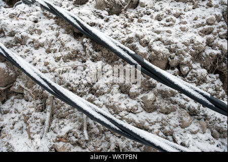 Laying a fiber optic and electricity cables in the frozen ground, buried cables for fast internet in rural region - underground cabling in Finland Stock Photo