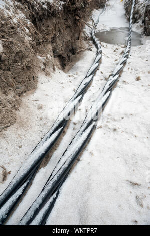 Laying a fiber optic and electricity cables in the frozen ground, buried cables for fast internet in rural region - underground cabling in Finland Stock Photo