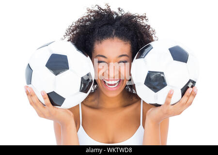 Pretty girl holding footballs and laughing at camera on white background Stock Photo