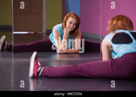 Pretty break dancer doing the splits looking in mirror in the dance studio Stock Photo