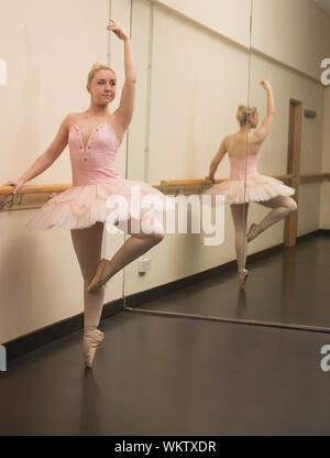 Beautiful ballerina standing en pointe with the barre in the dance studio Stock Photo