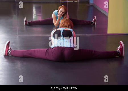 Pretty break dancer doing the splits looking in mirror in the dance studio Stock Photo