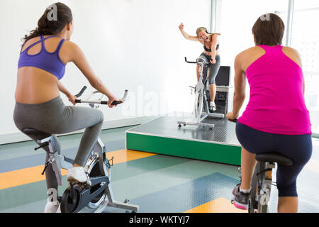 Spin class working out with motivational instructor at the gym Stock Photo