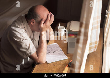 Tired old man holding hands on eyes after working on laptop. Top view Stock Photo