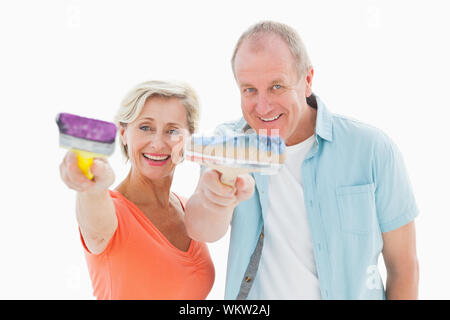 Happy older couple holding paintbrushes on white background Stock Photo