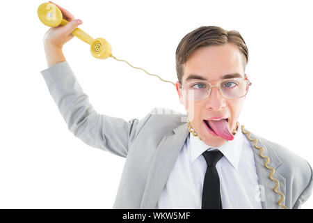 Geeky businessman being strangled by phone cord on white background Stock Photo