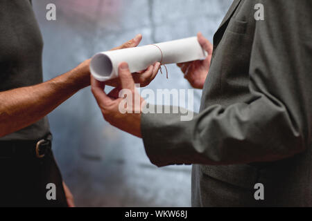 Architect handing blueprints to businessman. Stock Photo