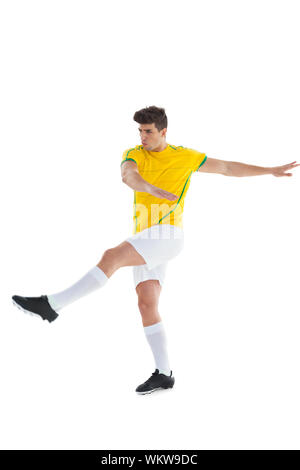 Football player in yellow jersey kicking on white background Stock Photo