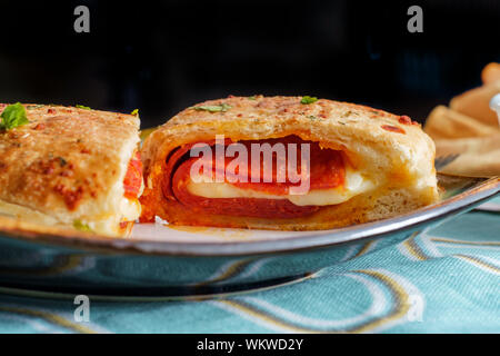 Italian pastry pepperoni and cheese calzone with tomato marinara dipping sauce Stock Photo