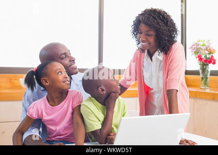 Cute siblings using laptop together with parents at home in the kitchen Stock Photo