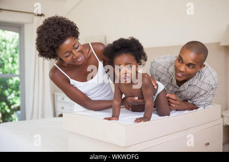 Happy parents with their baby girl on changing table at home in the bedroom Stock Photo