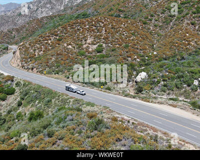 Asphalt road bends through Angeles National forests mountain, California, USA. Thin road winds between a ridge of hills and mountains at high altitude Stock Photo