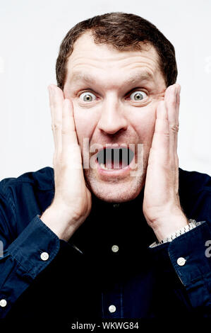 Screaming middle aged man covering his ears Stock Photo