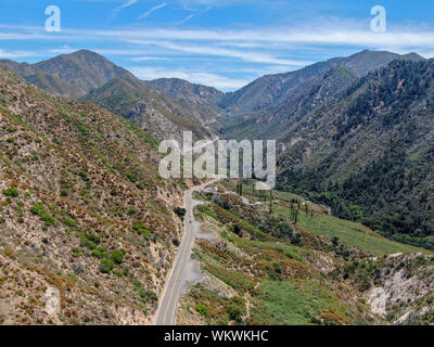 Asphalt road bends through Angeles National forests mountain, California, USA. Thin road winds between a ridge of hills and mountains at high altitude