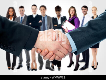 Closeup of shaking hands and business team in background Stock Photo