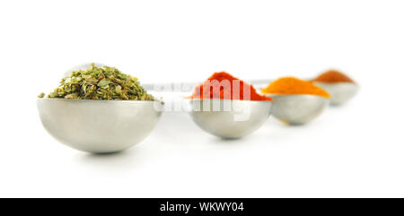 Assorted spices in metal measuring spoons on white background Stock Photo