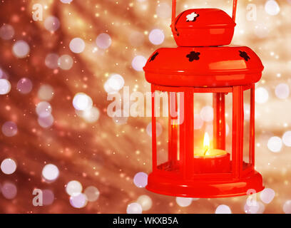 Red antique Christmas lantern with burning candle inside hanging on bokeh blur background, traditional Christmastime decoration Stock Photo