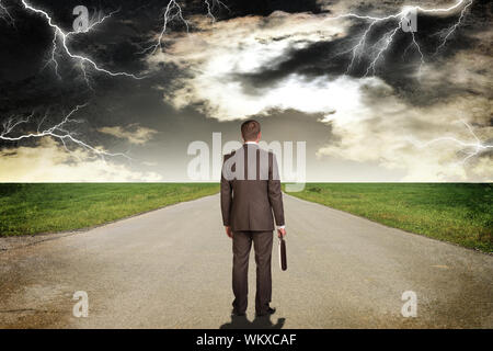 Businessman in suit with briefcase standing on the road. Rear view Stock Photo