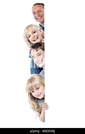 Happy family posing from behind blank whiteboard Stock Photo
