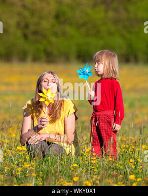 mother and son playing with pinwheels in a dandelion field Stock Photo ...