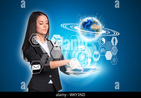 Beautiful businesswomen in suit using digital tablet. Earth and transparent hexagons with icons. Element of this image furnished by NASA Stock Photo