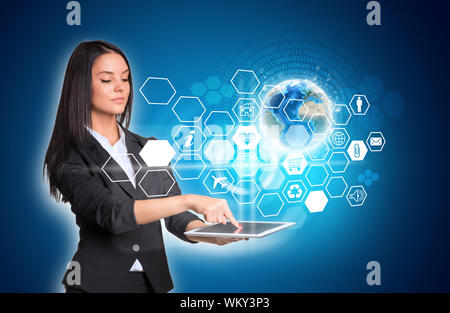 Beautiful businesswomen in suit using digital tablet. Earth and hexagons with icons. Element of this image furnished by NASA Stock Photo