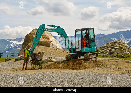 Maintenance workers moving ground with a mini excavator at the Pavillon cableway station of Skyway Monte Bianco in summer, Courmayeur, Aosta, Italy Stock Photo