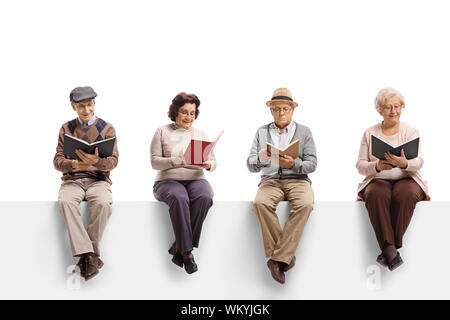 Group of elderly people sitting on a white panel reading books isolated on white background Stock Photo