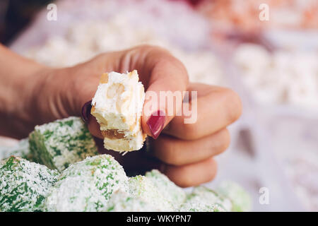 Woman hand holding Turkish Delight on colorful turkish delight background Stock Photo