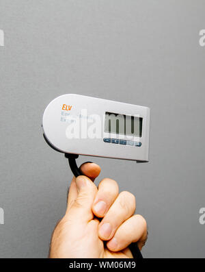 Paris, France - Oct 21, 2017: Man hand holding ELW energy meter made in Germany isolated on gray background Stock Photo